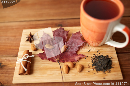 Image of cup of tea, maple leaf and almond on wooden board