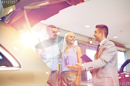 Image of happy couple with car dealer in auto show or salon