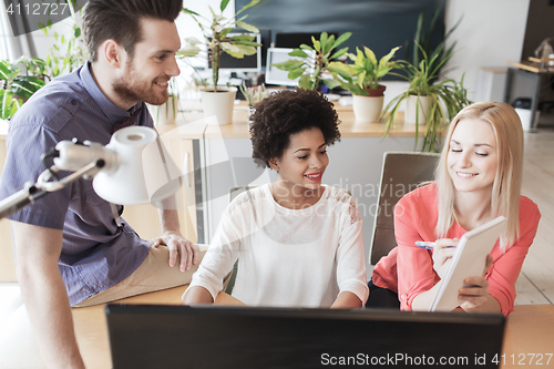 Image of happy creative team with computer in office