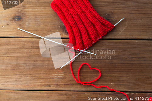 Image of knitting needles and thread in heart shape on wood