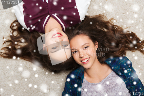 Image of happy smiling pretty teenage girls lying on floor