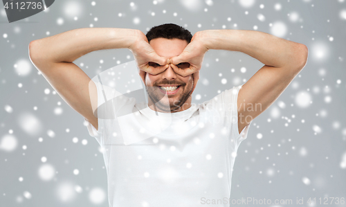 Image of man making finger glasses over snow