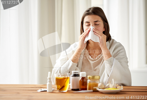 Image of sick woman with medicine blowing nose to wipe