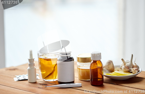 Image of drugs, thermometer, honey and cup of tea on wood