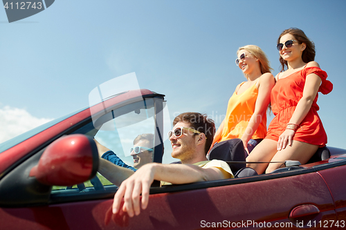 Image of happy friends driving in cabriolet car