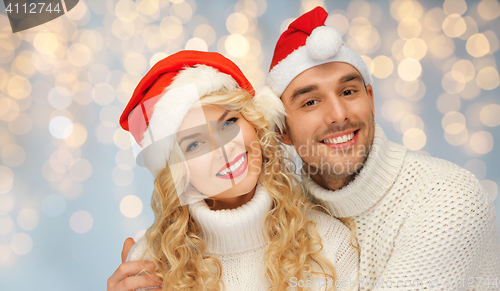 Image of happy family couple in sweaters and santa hats