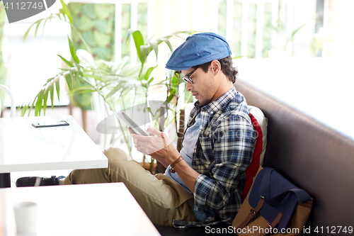 Image of man with tablet pc sitting at cafe table