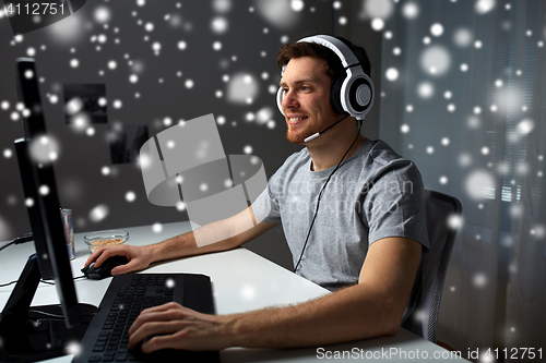 Image of man in headset playing computer video game at home