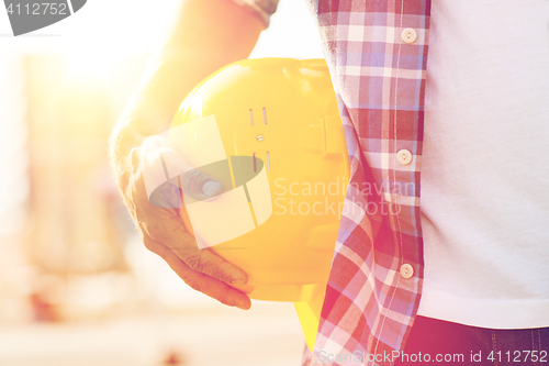 Image of close up of builder hand holding hardhat outdoors