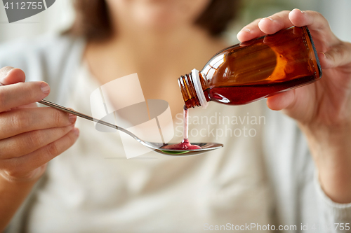 Image of woman pouring medication from bottle to spoon