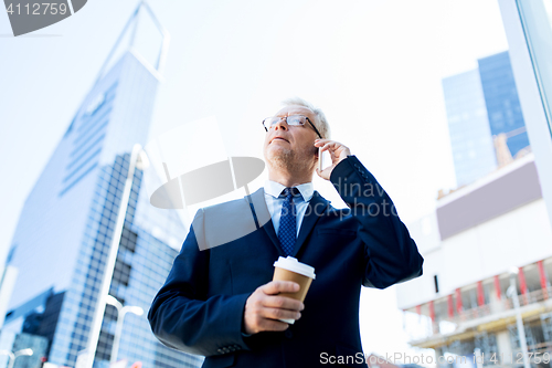 Image of senior businessman calling on smartphone in city