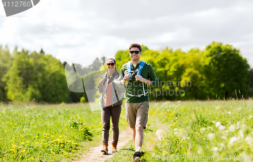 Image of happy couple with backpacks hiking outdoors