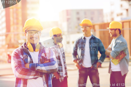 Image of group of smiling builders in hardhats outdoors