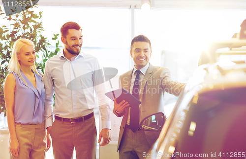 Image of happy couple with car dealer in auto show or salon