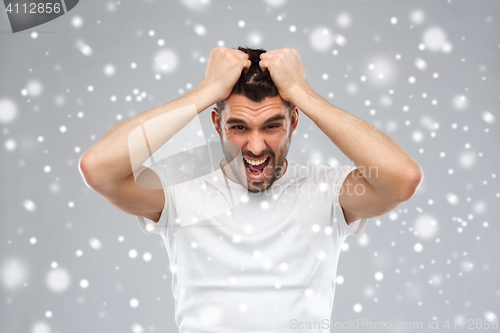 Image of crazy shouting man in t-shirt over snow background