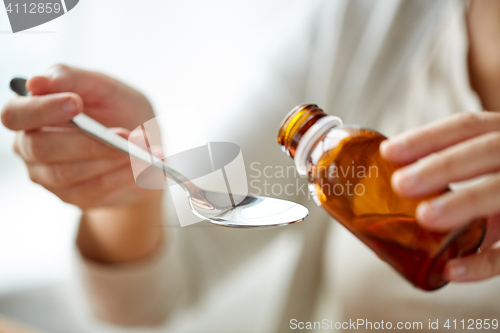 Image of woman pouring medication from bottle to spoon