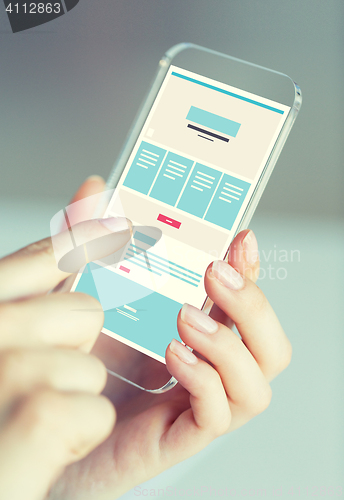 Image of close up of hands with web design on smartphone