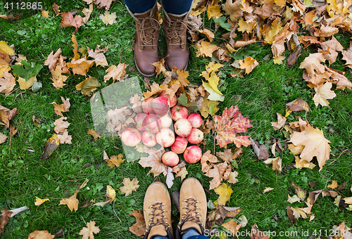 Image of feet in boots with apples and autumn leaves