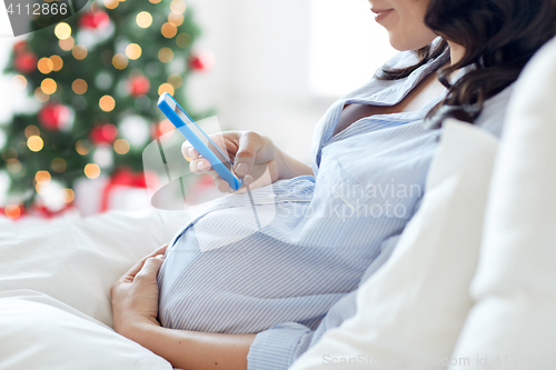 Image of close up of pregnant woman with smartphone in bed