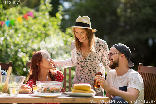 Image of happy friends having dinner at summer garden party