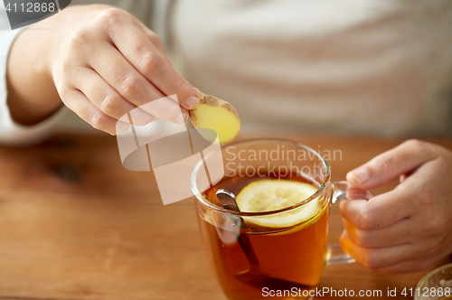 Image of close up of woman adding ginger to tea with lemon