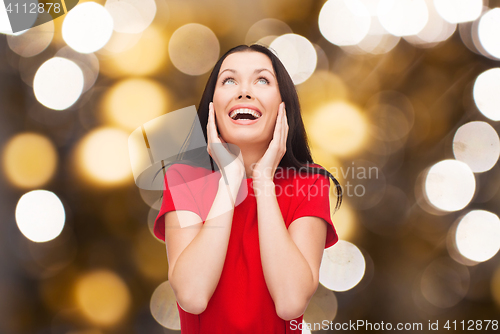 Image of amazed laughing woman in red dress looking up