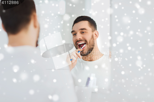 Image of man with toothbrush cleaning teeth at bathroom