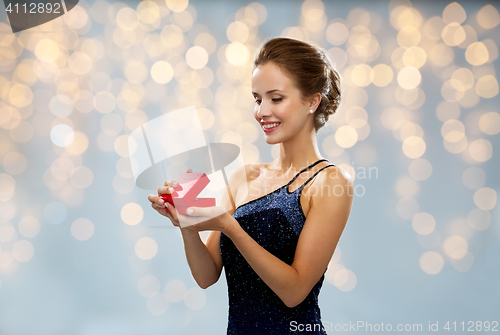 Image of smiling woman holding red gift box over lights