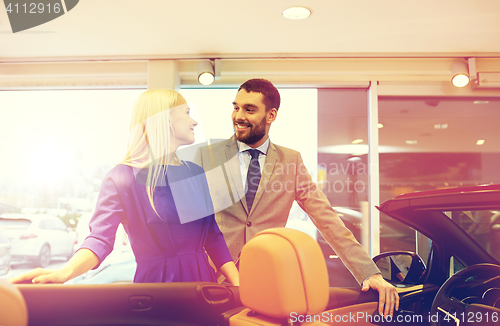 Image of happy couple buying car in auto show or salon