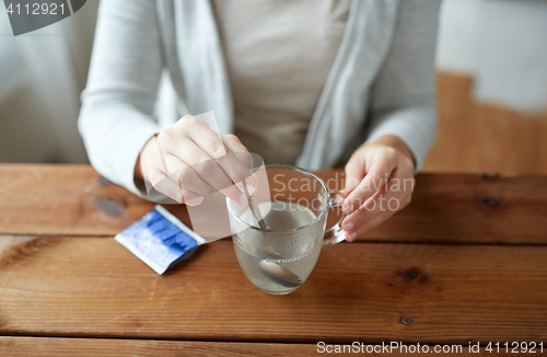 Image of woman stirring medication in cup with spoon