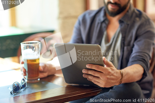 Image of close up of man with tablet pc and beer at pub