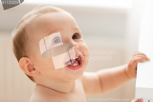 Image of happy little baby boy or girl at home looking up