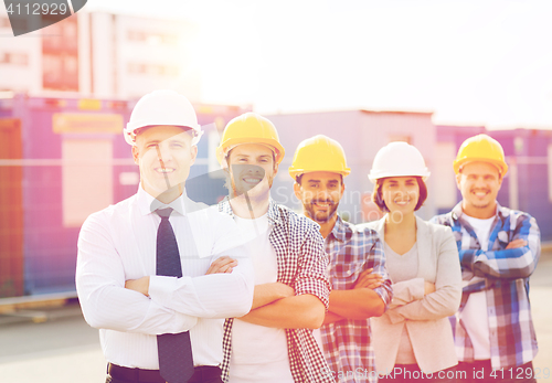 Image of group of smiling builders in hardhats outdoors