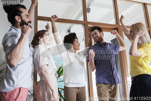 Image of happy creative team celebrating victory in office