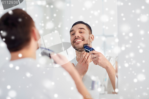 Image of man shaving beard with trimmer at bathroom