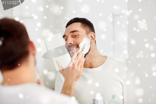 Image of happy man applying shaving foam at bathroom mirror