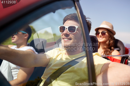 Image of happy friends driving in cabriolet car