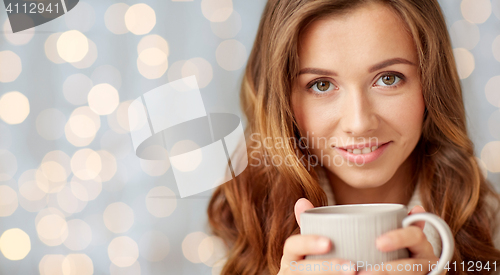 Image of close up of happy woman with tea cup over lights