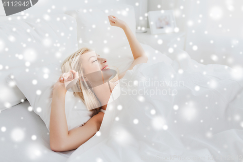 Image of young woman stretching in bed at home bedroom