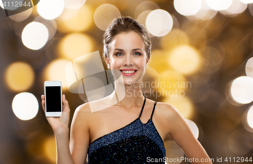 Image of smiling woman in evening dress holding smartphone