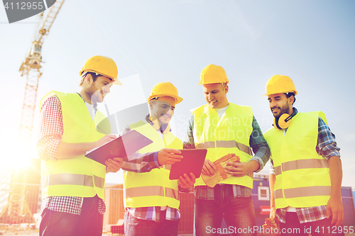 Image of group of smiling builders with tablet pc outdoors