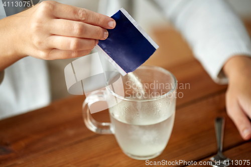 Image of woman pouring medication into cup of water