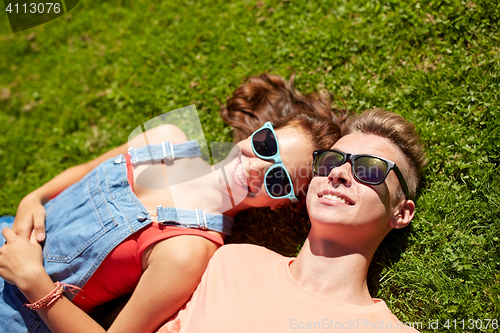 Image of happy teenage couple lying on grass at summer