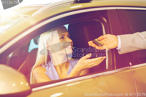 Image of happy woman getting car key in auto show or salon