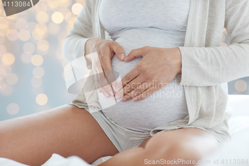 Image of close up of pregnant woman making heart gesture