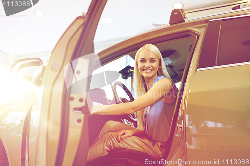 Image of happy woman inside car in auto show or salon