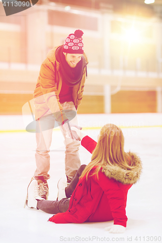 Image of man helping women to rise up on skating rink