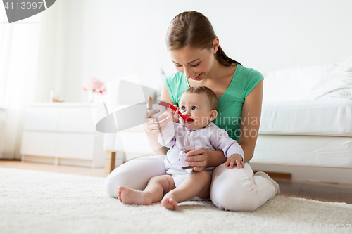 Image of mother with spoon feeding little baby at home