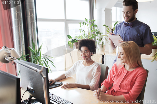 Image of happy creative team with computer in office