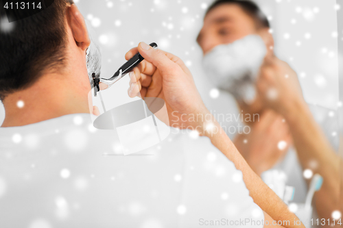 Image of close up of man shaving beard with razor blade